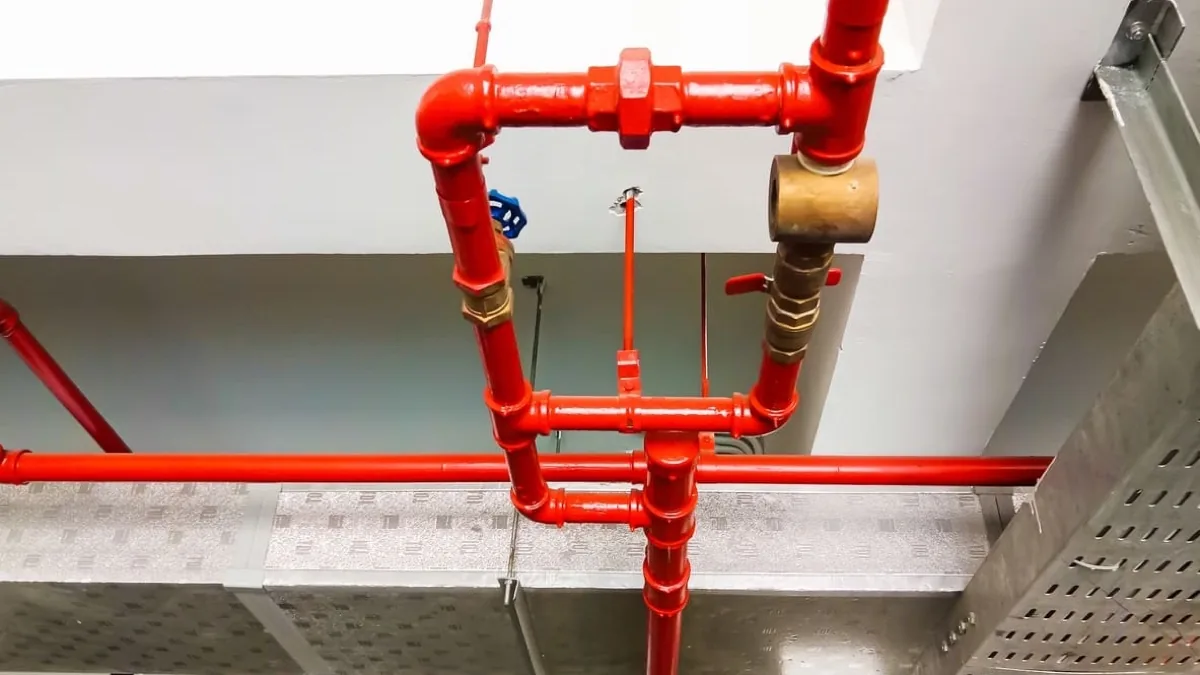 Red commercial fire-sprinkler pipework installed above a ceiling service zone